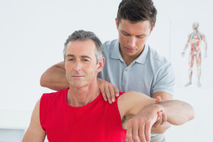 A physiotherapist assessing a man's shoulder range of motion.